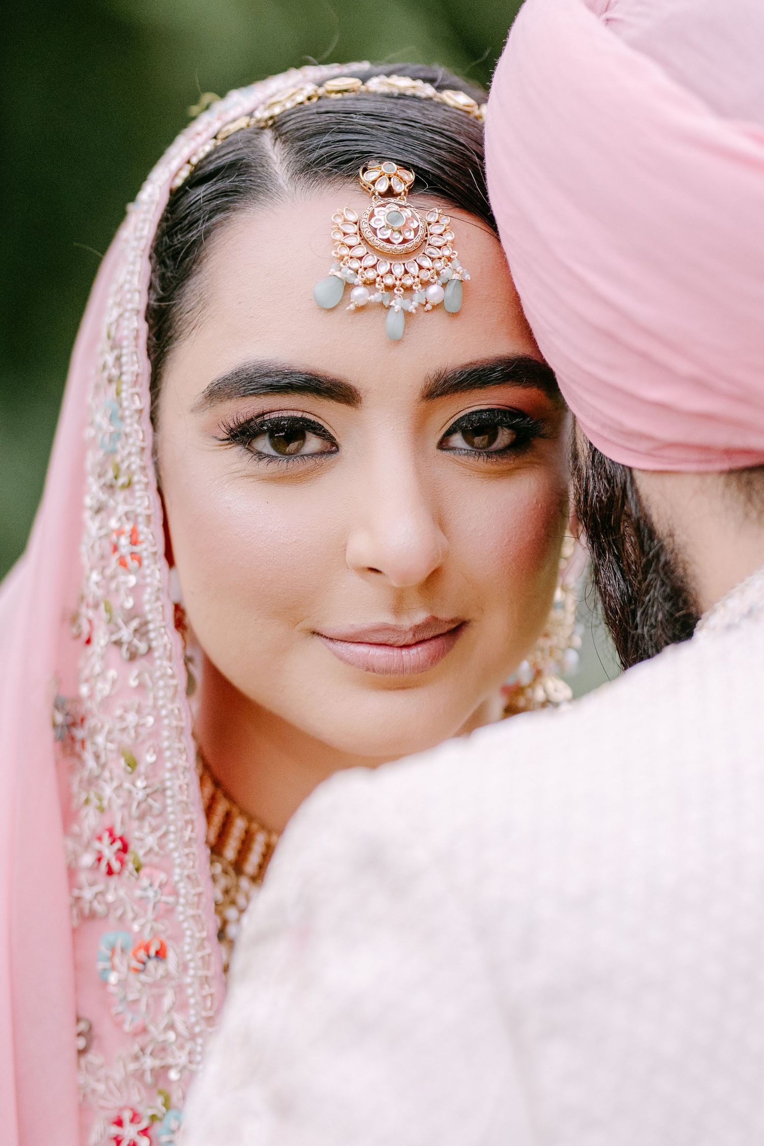 Traditional South Asian bridal jewelry and makeup with intricate headpiece details.
