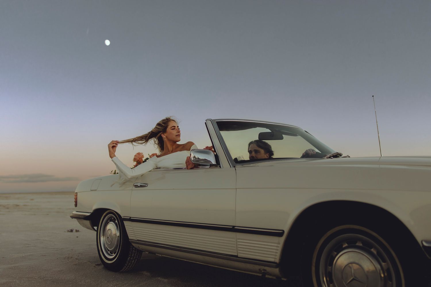lumenali photography: eloping couple drives across the frame as the moon rises in the background.