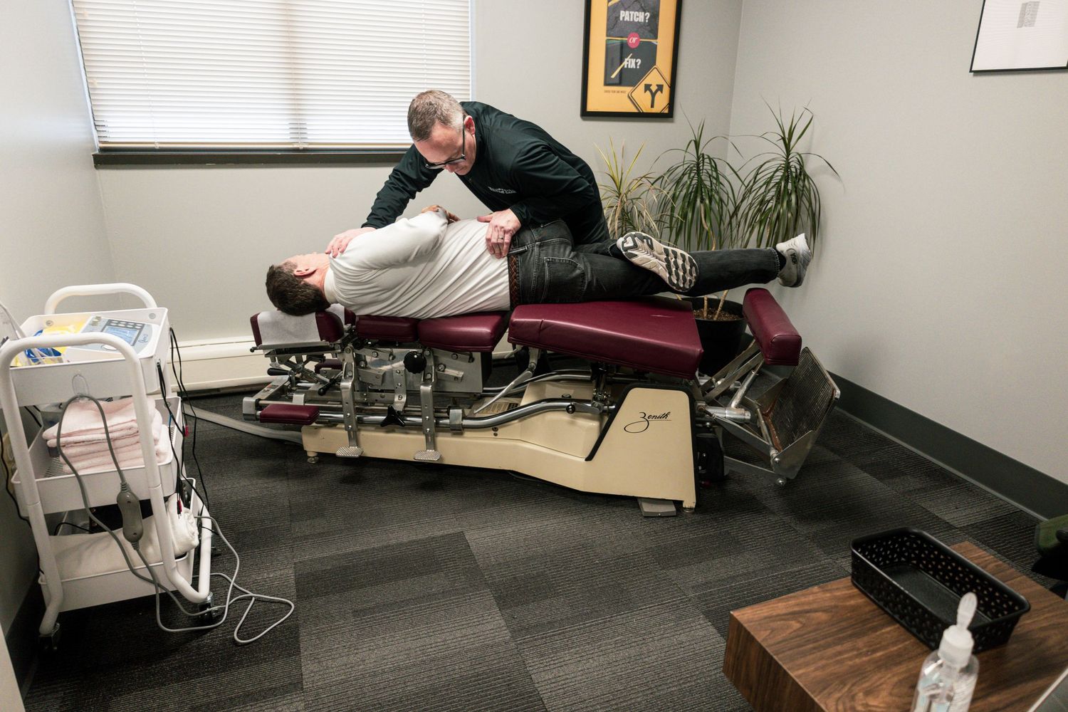 Chiropractor performing adjustment treatment on patient lying on red treatment table.