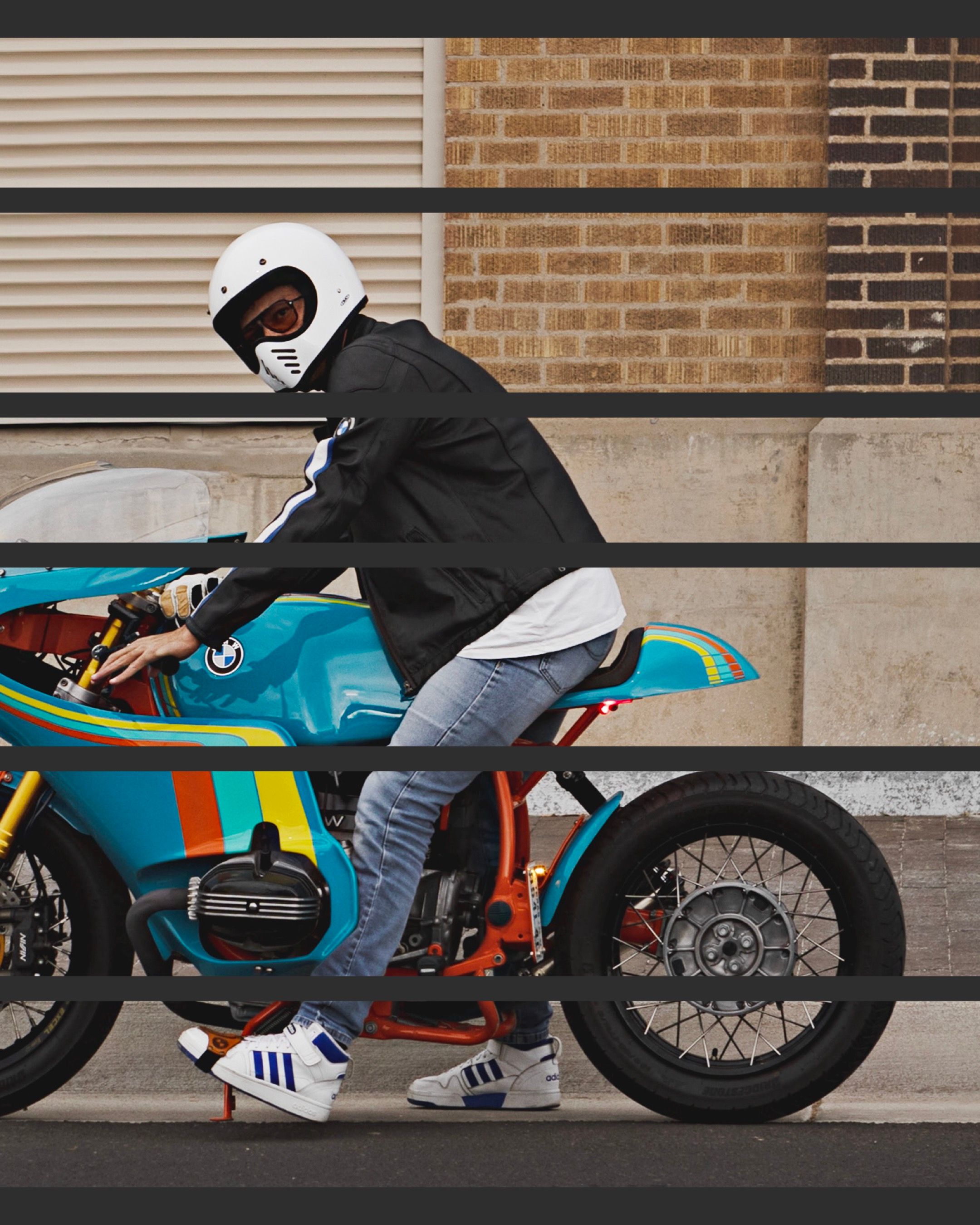 Rider on custom BMW cafe racer motorcycle against brick wall backdrop.