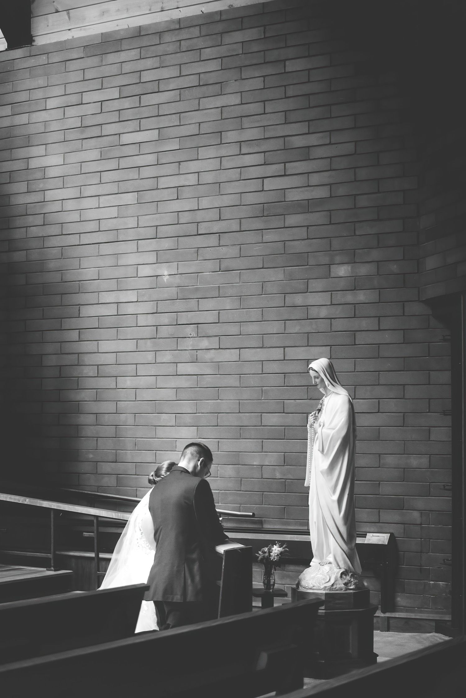 Black and white image of people praying in church pews.