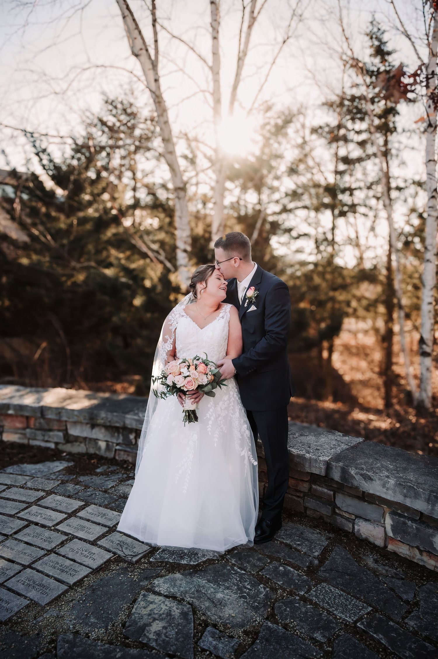 Newlyweds sharing an intimate moment on a stone wall during winter.