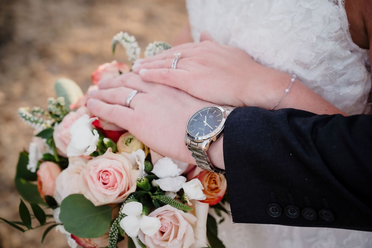 Close-up of wedding rings and pink roses on a decorative display.