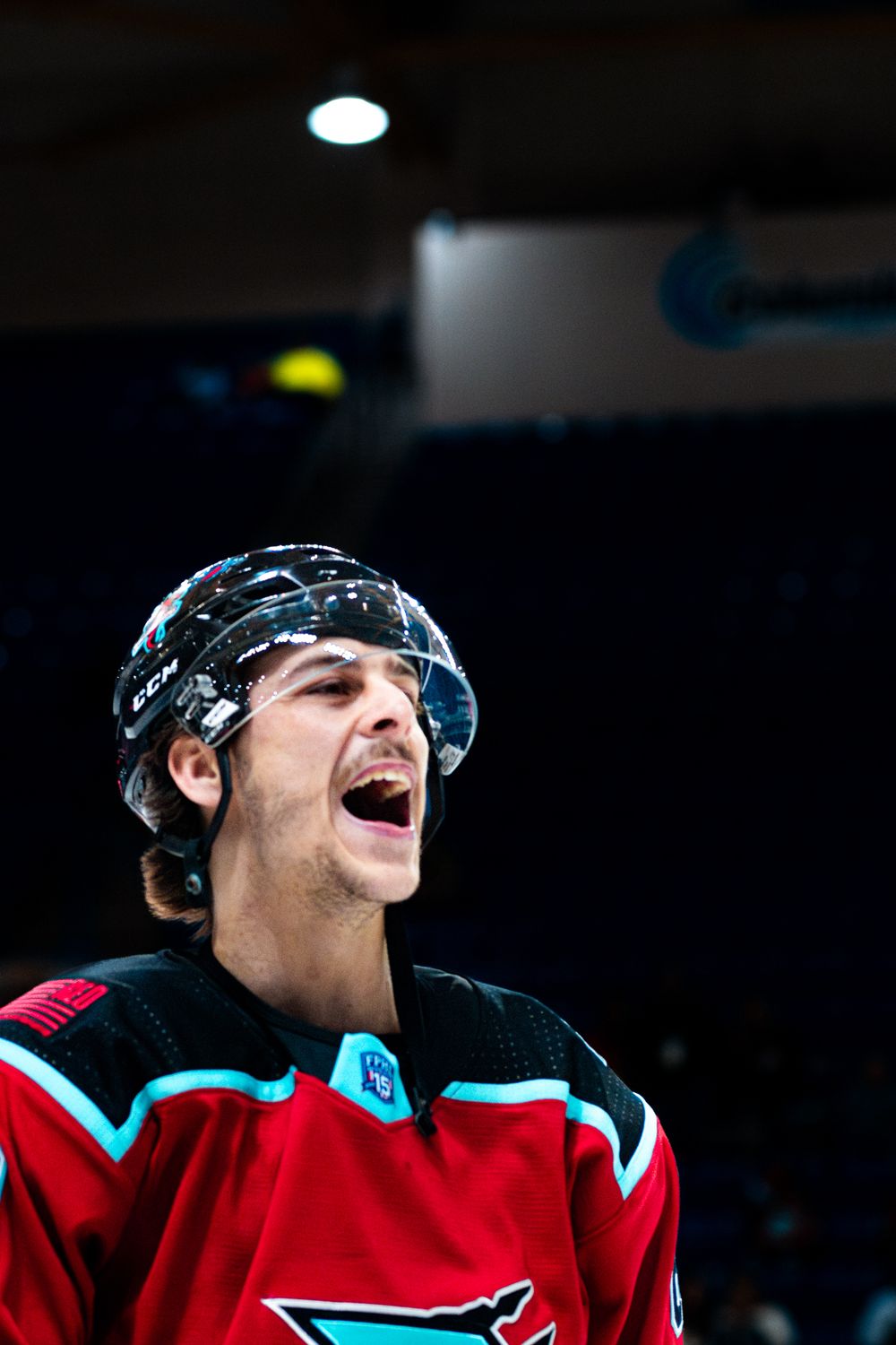 A hockey player in a red San Jose Sharks jersey celebrates with enthusiasm during a game.