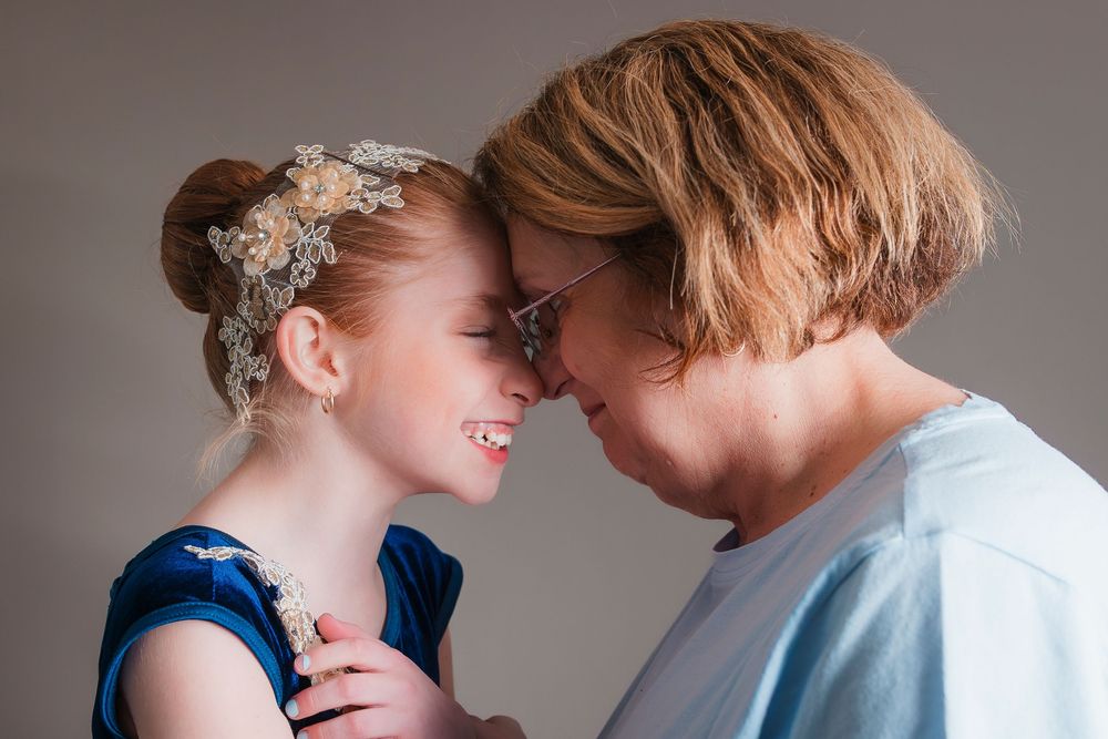 A couple sharing an intimate tender moment with foreheads touching, one wearing a blue dress with crystal hair accessory.