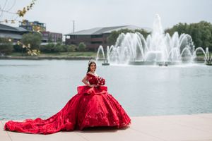 Dramatic red dress captured near a fountain with water features in the background.