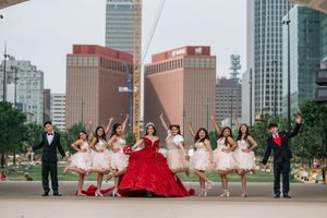 Celebratory group photo with attendants in pink dresses against urban architecture.
