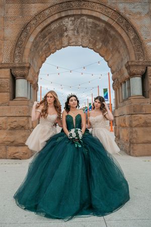 Emerald green ballgown with tulle skirt photographed under stone archways with string lights.