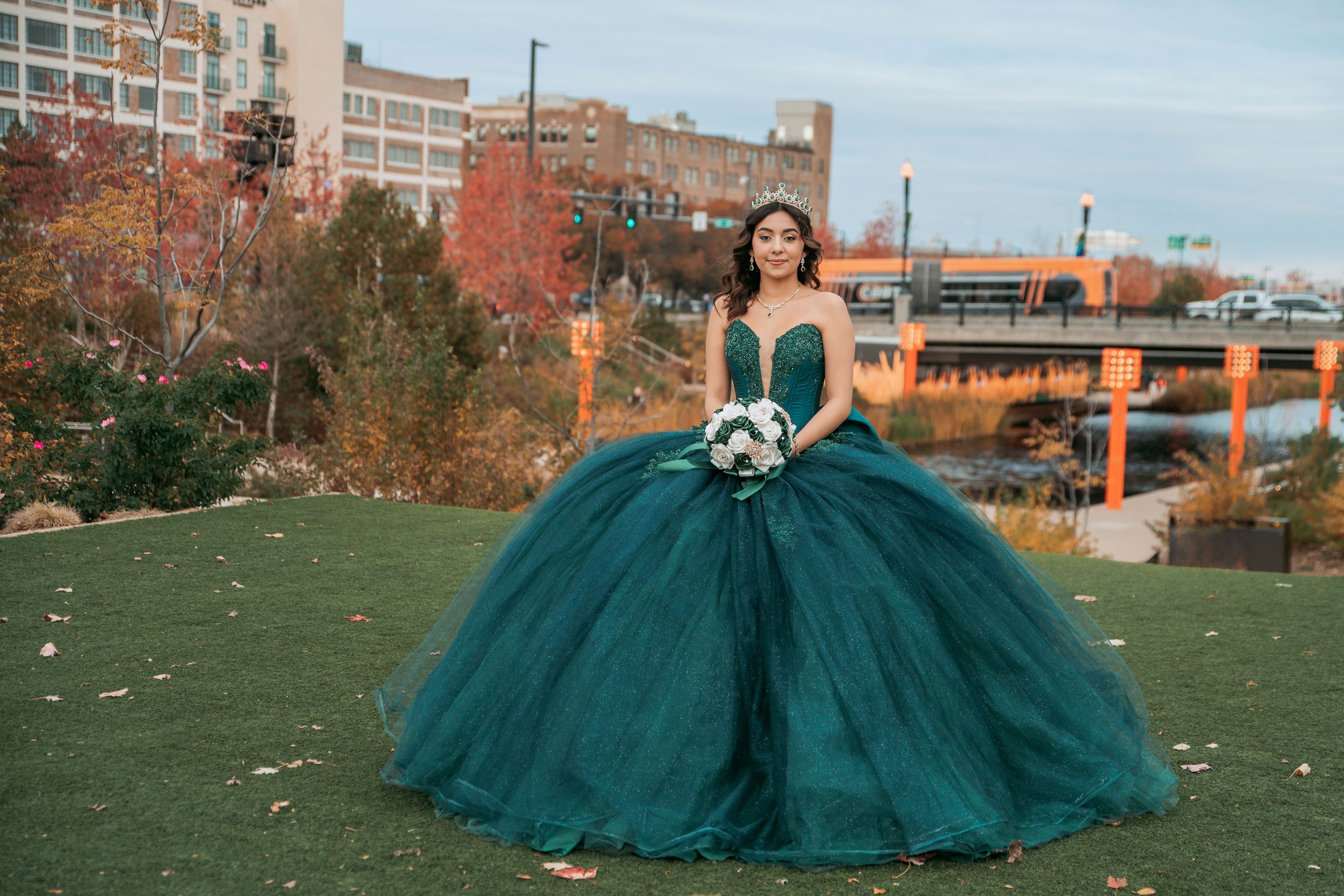 Emerald green ball gown photographed in an autumn urban setting with fall foliage.