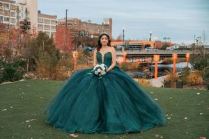 Elegant emerald green formal dress photographed outdoors against autumn scenery.