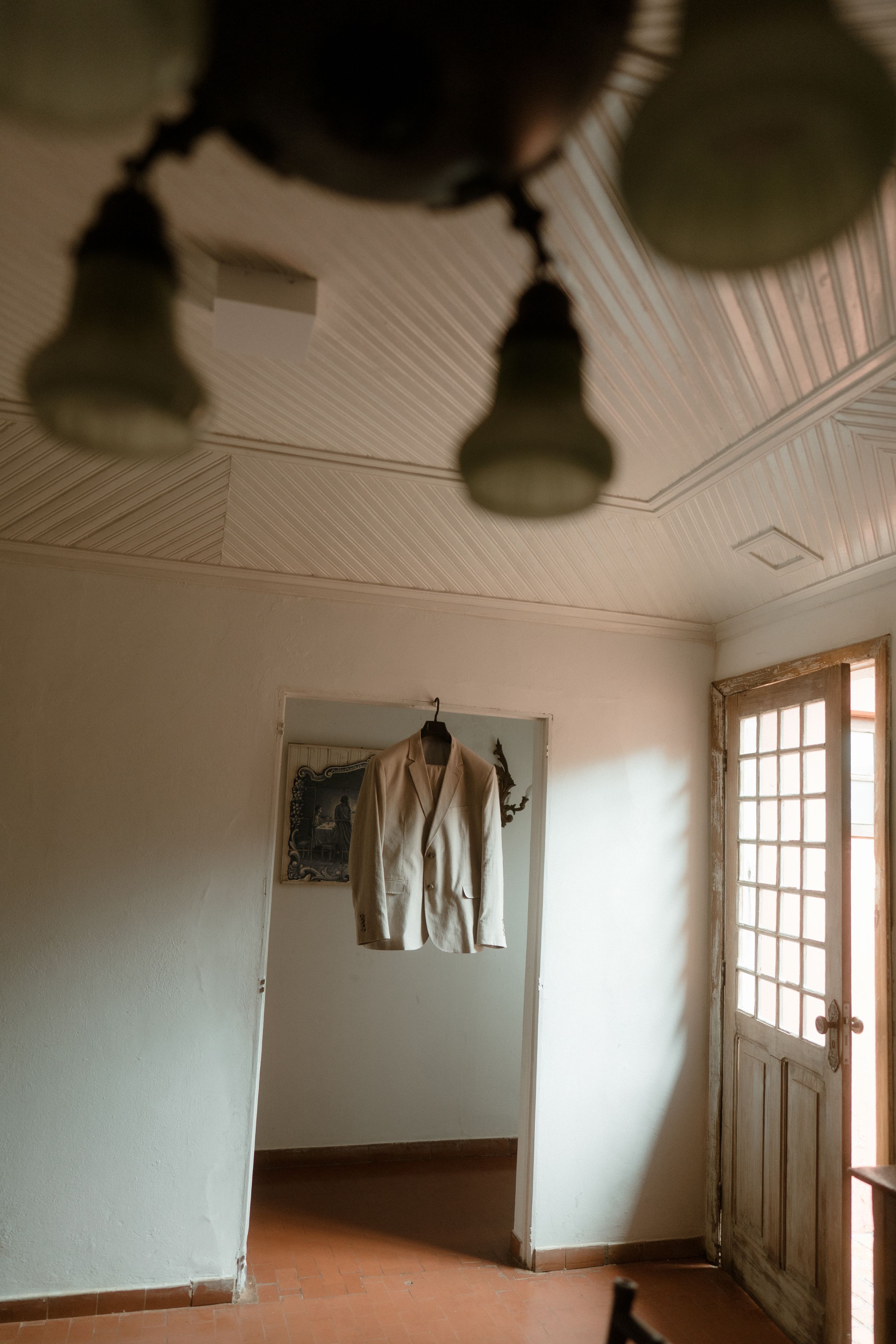 Minimalist room interior with hanging suit jacket and vintage lighting fixtures.