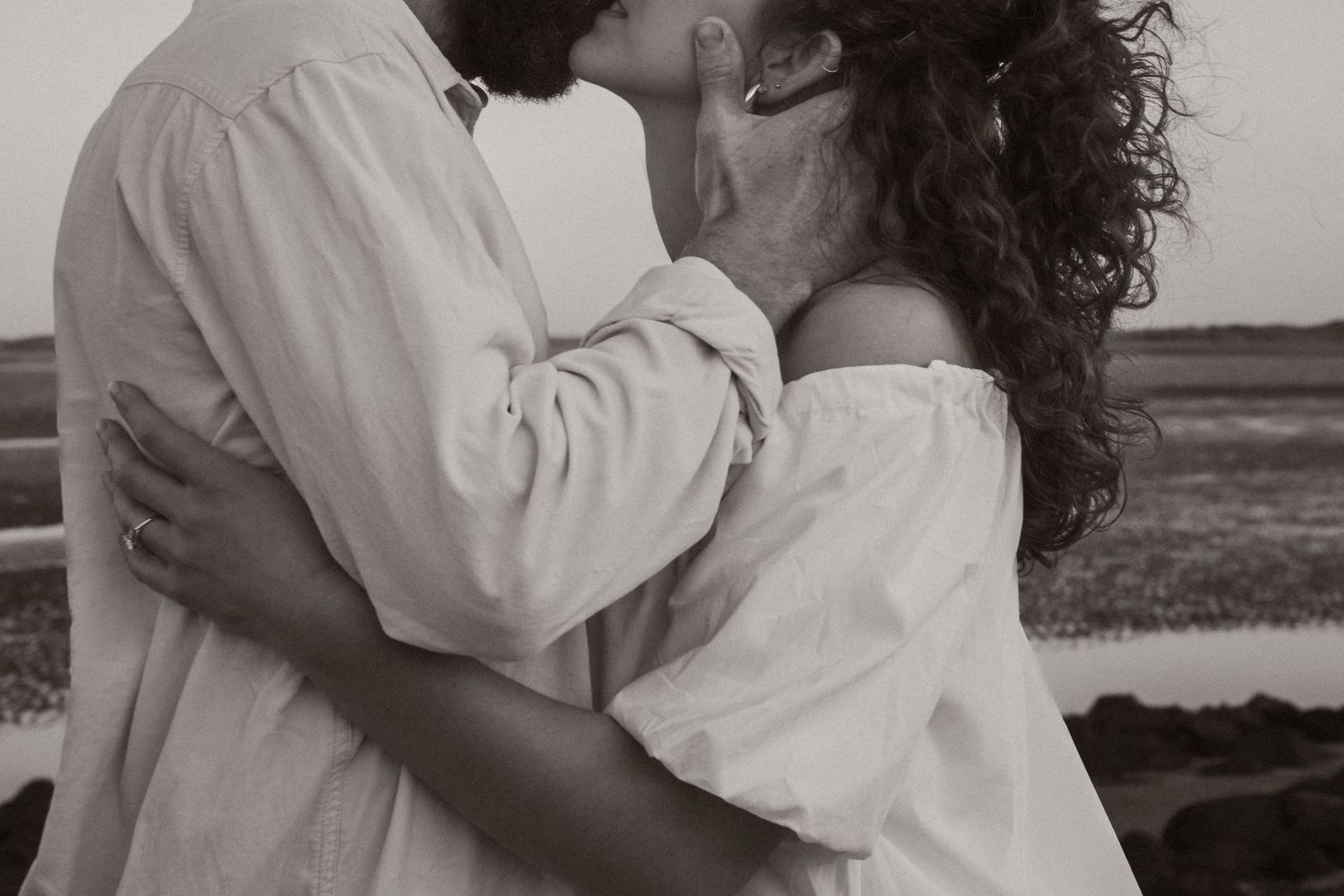 Intimate black and white portrait capturing a tender embrace outdoors.