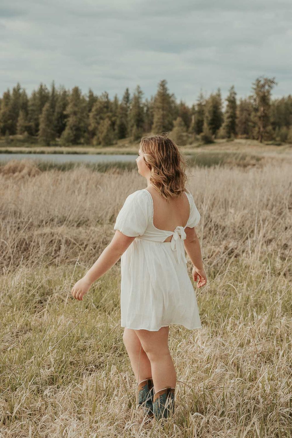 Outdoor senior portraits for high school graduate in Eastern Washington wearing a white dress in an open country field