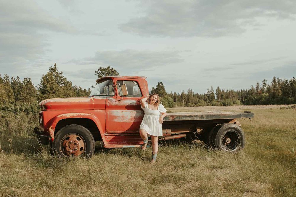 Senior girl from Davenport High School posing in vintage red truck during rustic senior photos at The Point at Horseshoe Lake near Spokane
