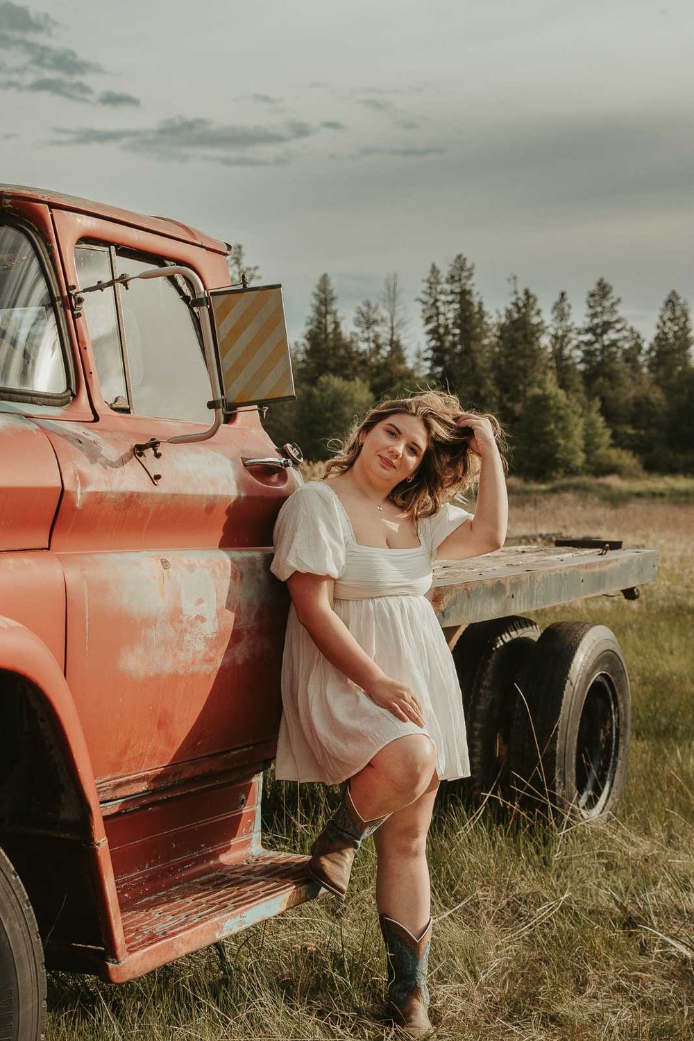 Senior girl from Davenport High School posing in vintage red truck during rustic senior photos at The Point at Horseshoe Lake near Spokane