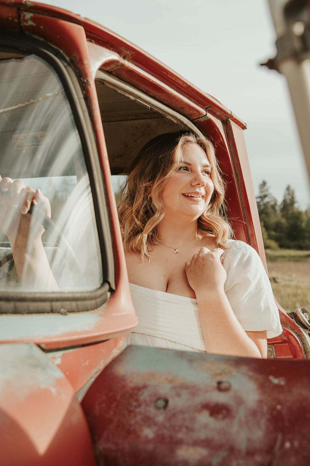 Senior girl from Davenport High School posing in vintage red truck during rustic senior photos at The Point at Horseshoe Lake near Spokane