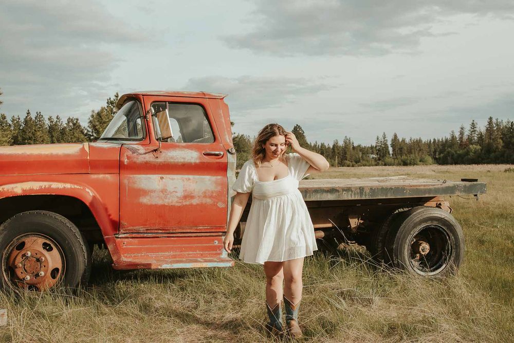Senior girl from Davenport High School posing in vintage red truck during rustic senior photos at The Point at Horseshoe Lake near Spokane