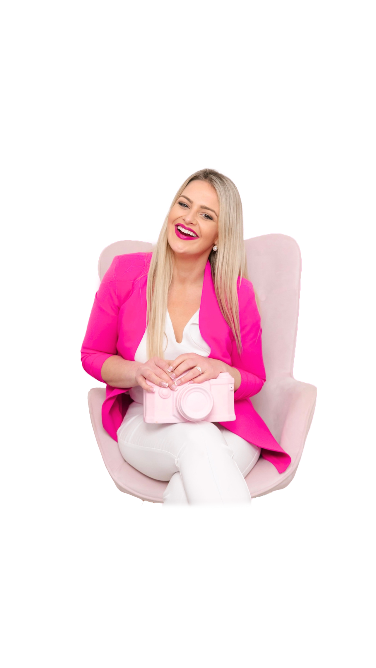 Professional wearing bright pink blazer and white outfit sitting in light pink chair with decorative pink camera.