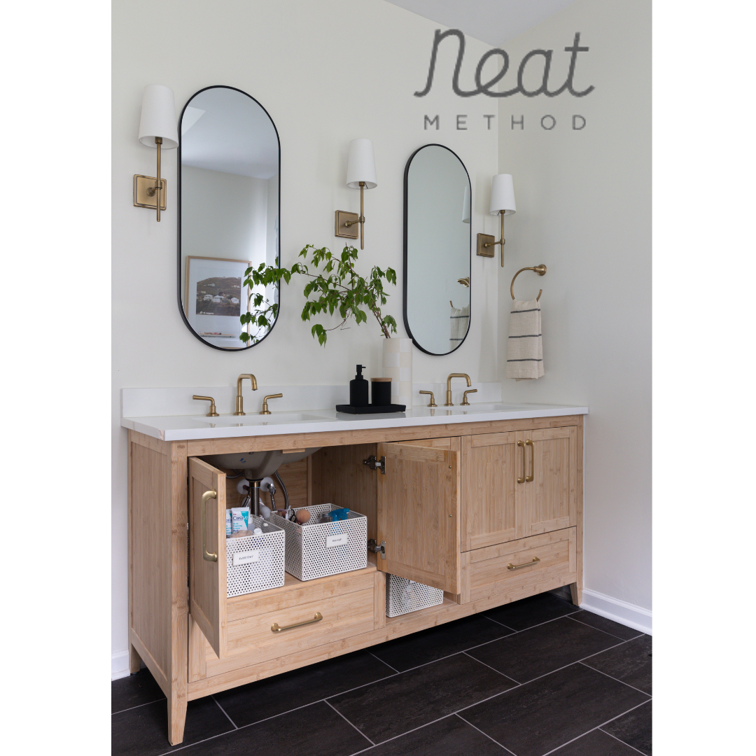 Heather Ison Photography for Neat Method. Modern bathroom vanity with arched mirrors, light wood cabinets, and black tile flooring.