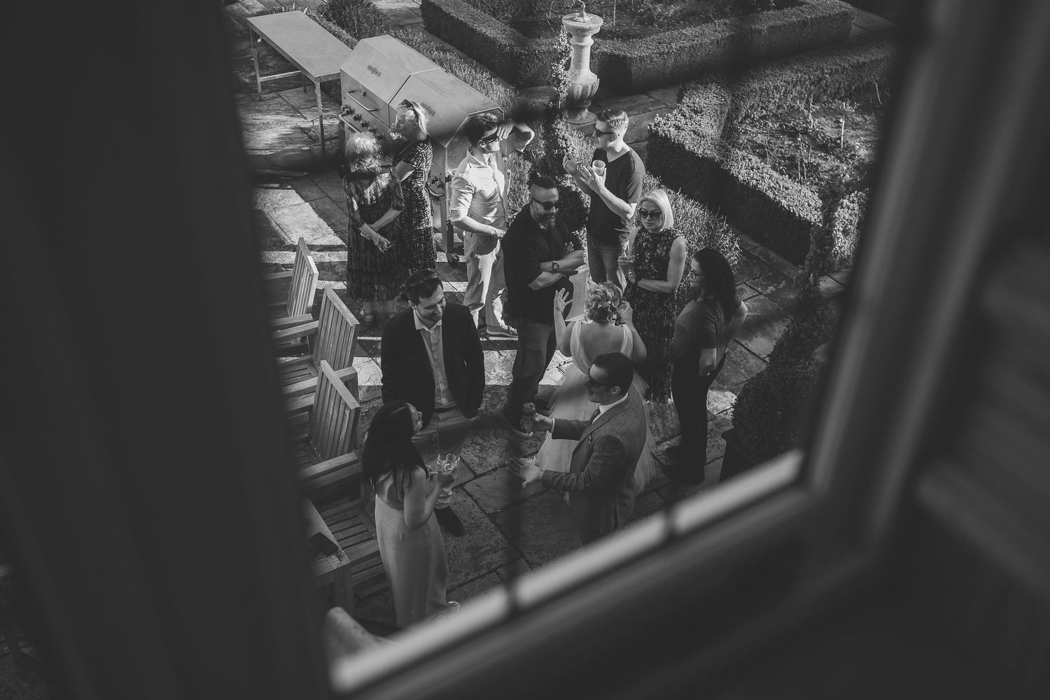 A black and white aerial view through a window showing a group of people gathered on outdoor steps.