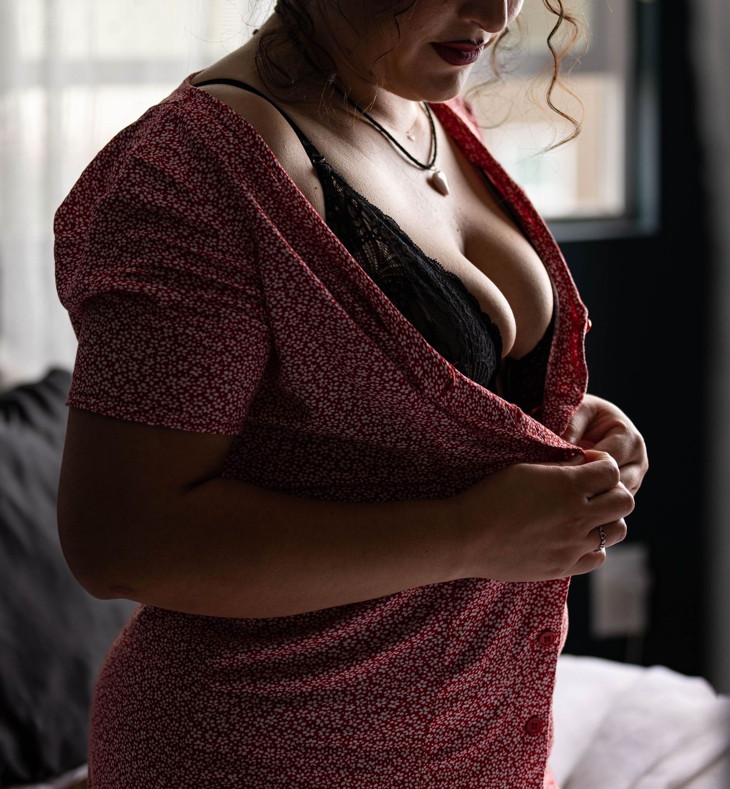Woman undressing in bedroom captured by Los Angeles boudoir photographer.