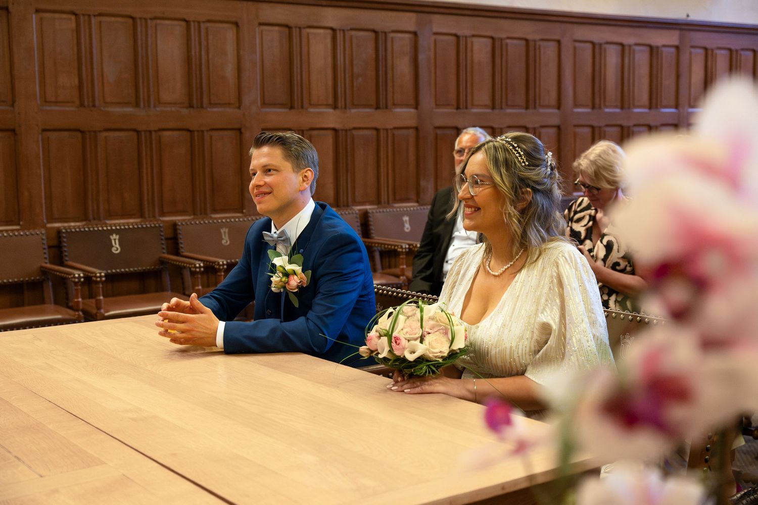 A wedding couple seated at wooden tables during their indoor church ceremony.