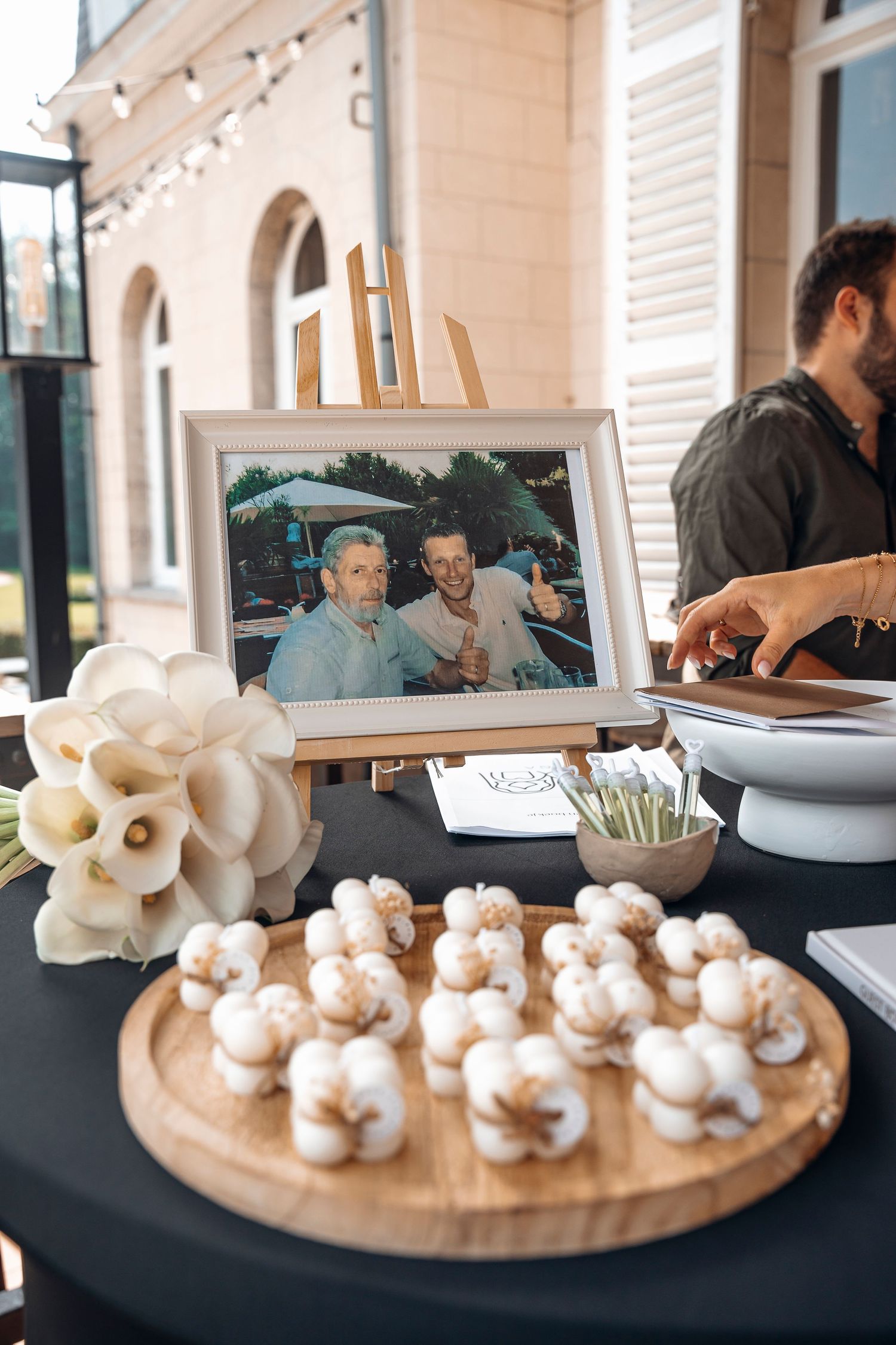Wedding reception table with framed photo, white flowers and decorative treats.
