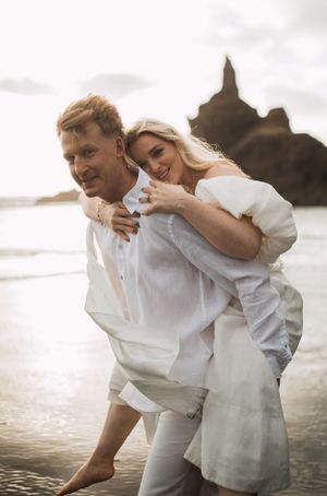 Playful beach photoshoot at sunset with waves crashing in the background.