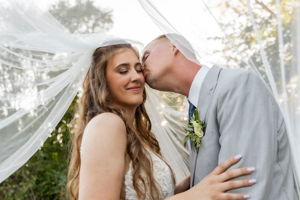 Wedding couple kissing under the veil at The Chateau on their wedding day in Cambridge, Iowa