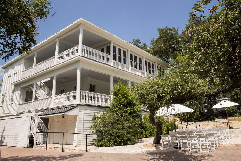 Elegant white wedding venue with double-story porches and outdoor seating area.