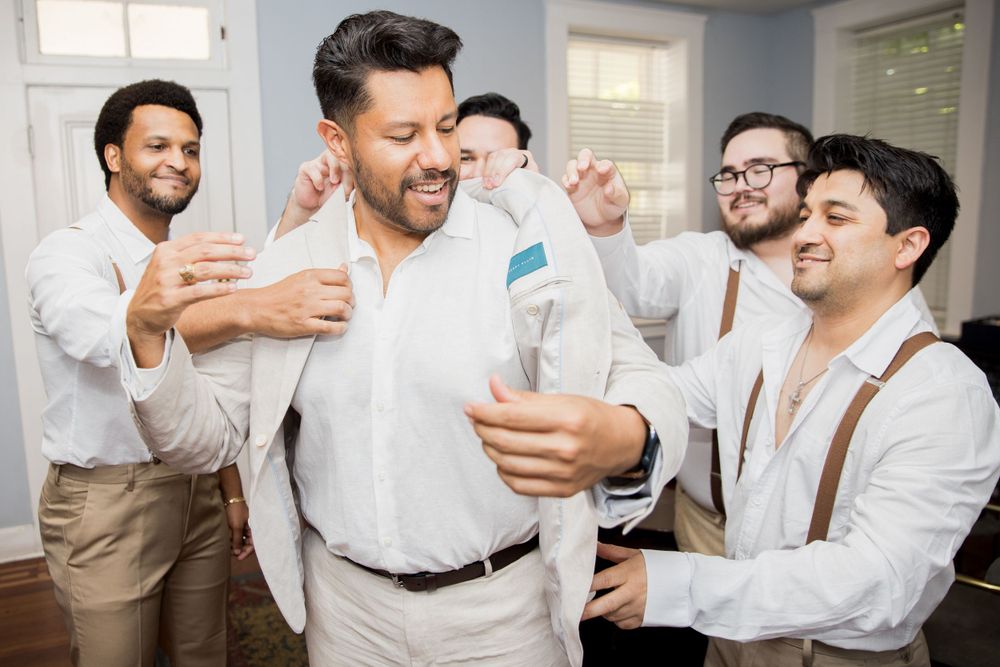 Group in white shirts and suspenders sharing laughs during preparation.