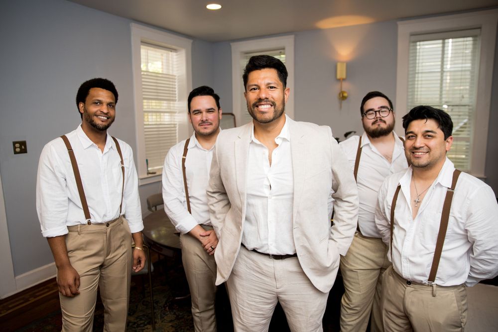 Groomsmen in matching attire standing together in indoor setting.