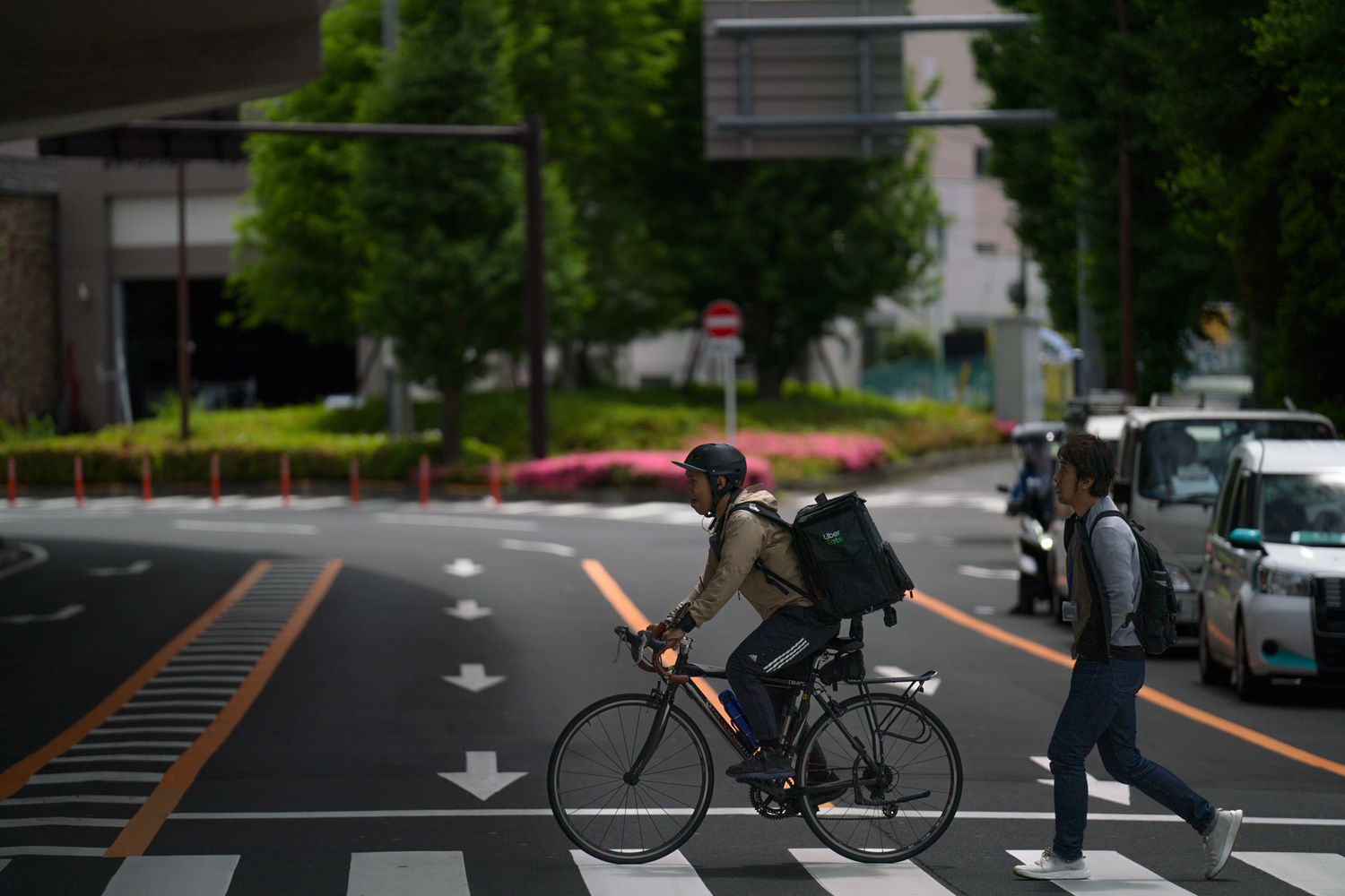 Cyclist crossing urban street intersection on a cloudy day.