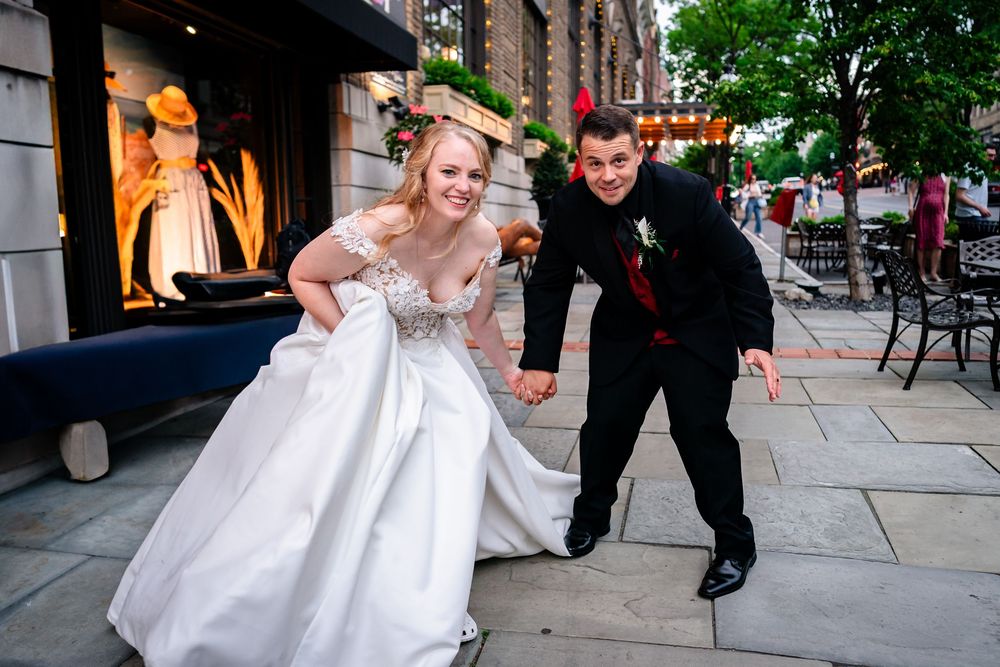 Wedding couple dips and twirls dramatically on city sidewalk during photo session.