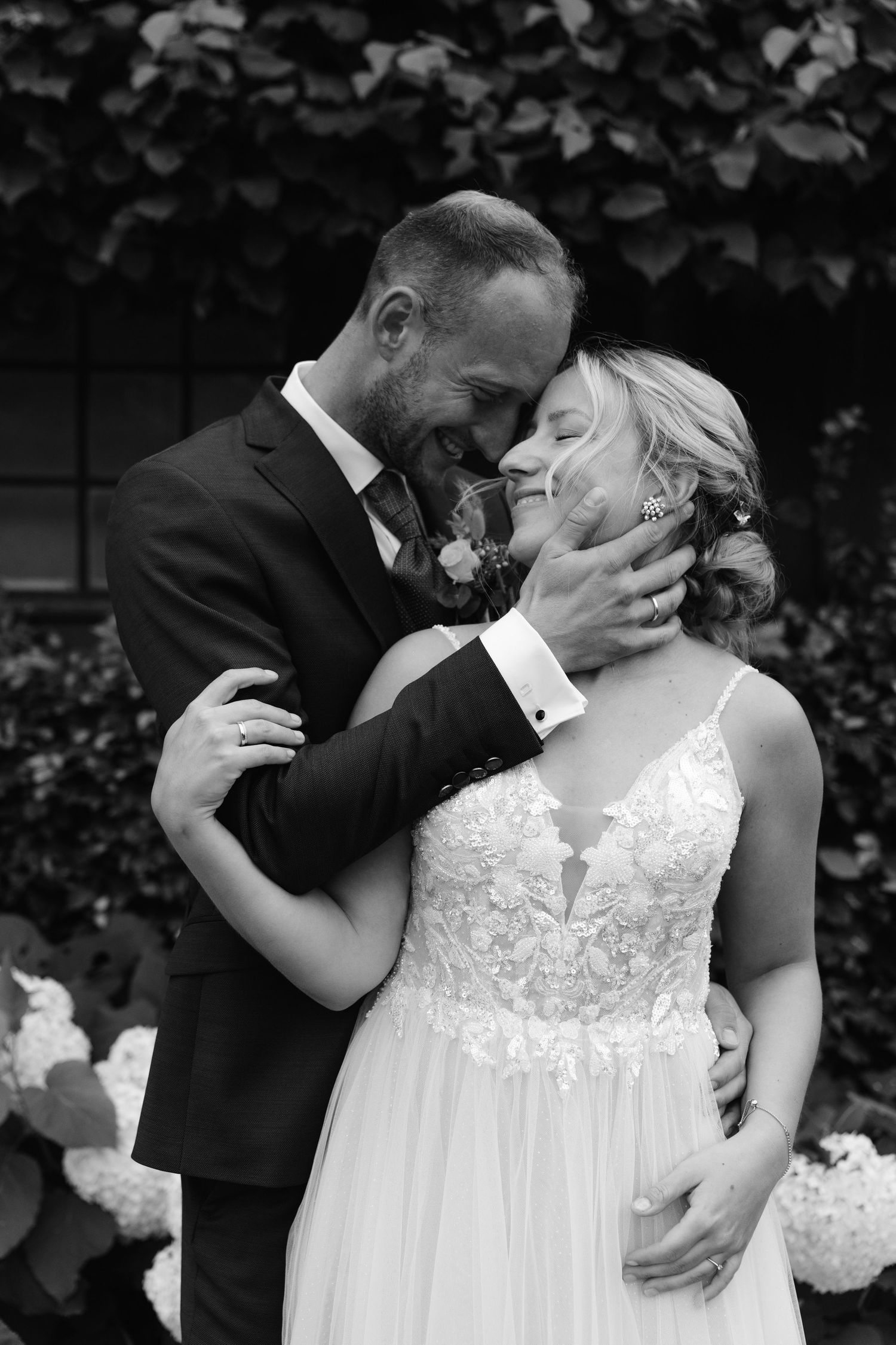 An intimate black and white wedding portrait showing a tender moment between newlyweds.