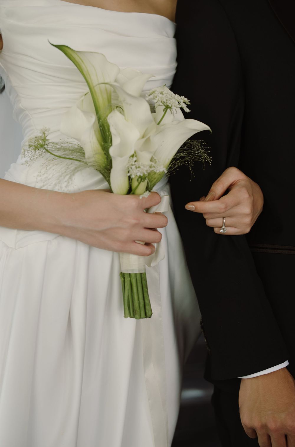 Close-up details of white wedding bouquet and dress fabrics showing elegant floral arrangements.