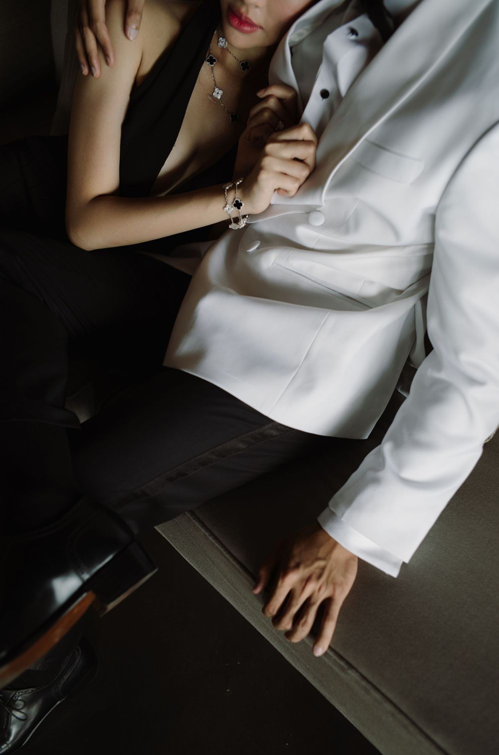 Close-up view of a white formal outfit with hands visible against a dark background.