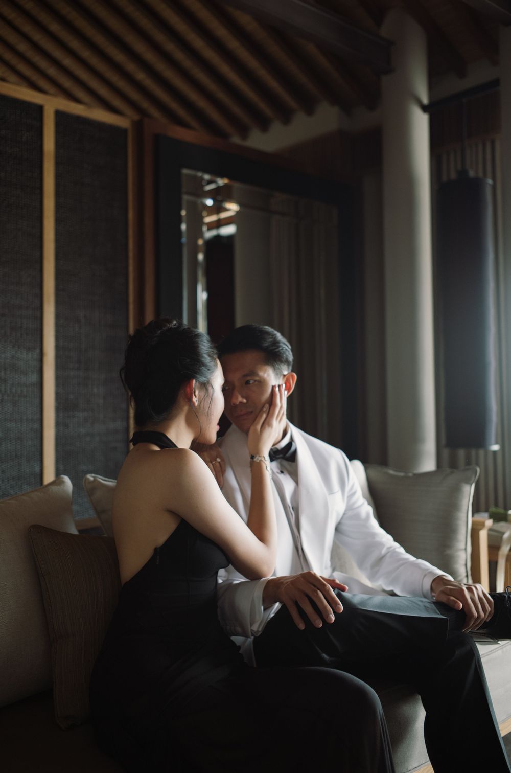 Intimate moment captured of a couple sharing a tender moment on a couch in moody lighting.