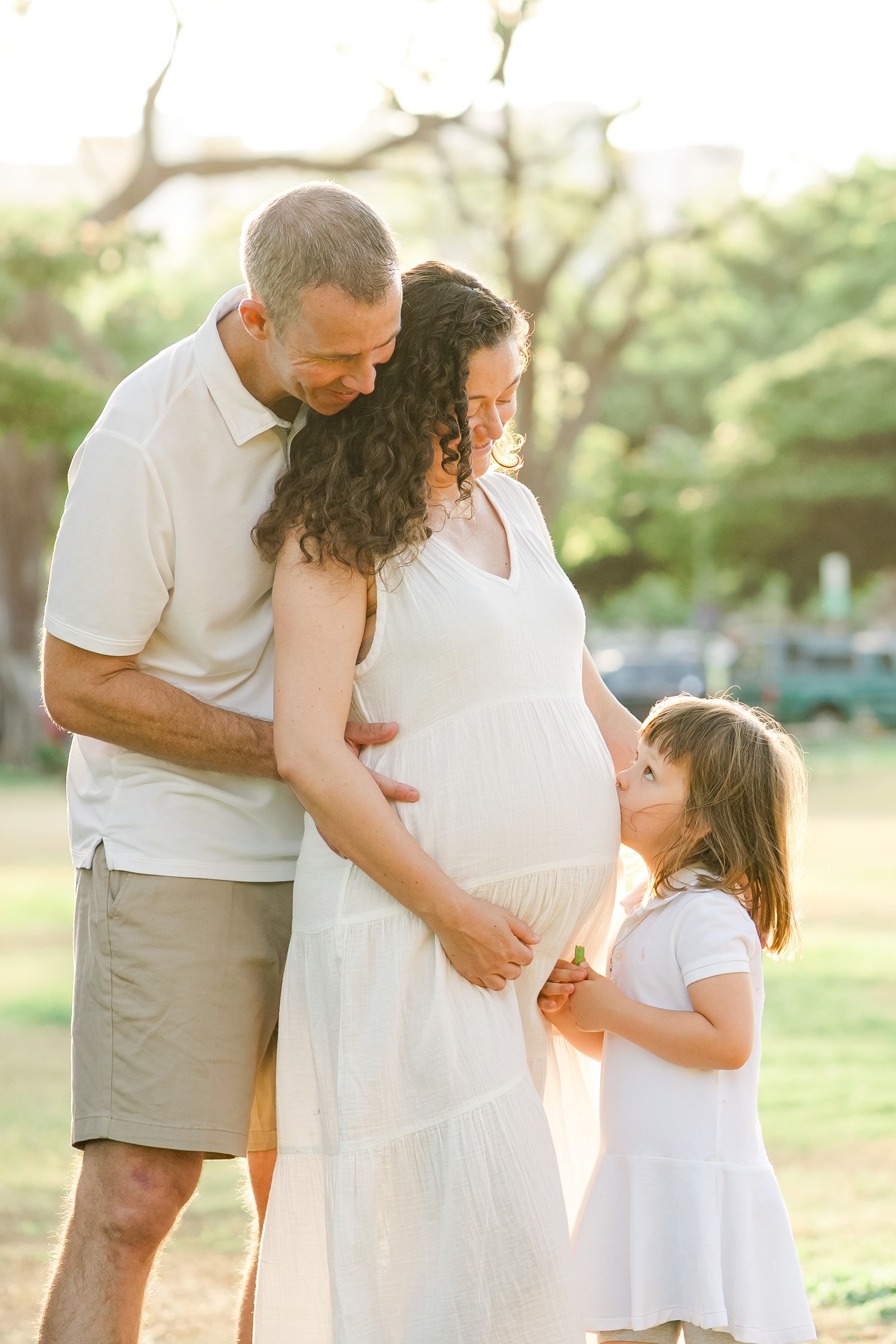 Sunlit outdoor engagement or family photography session captured through multiple frames in a wooded setting. Oahu family photographer