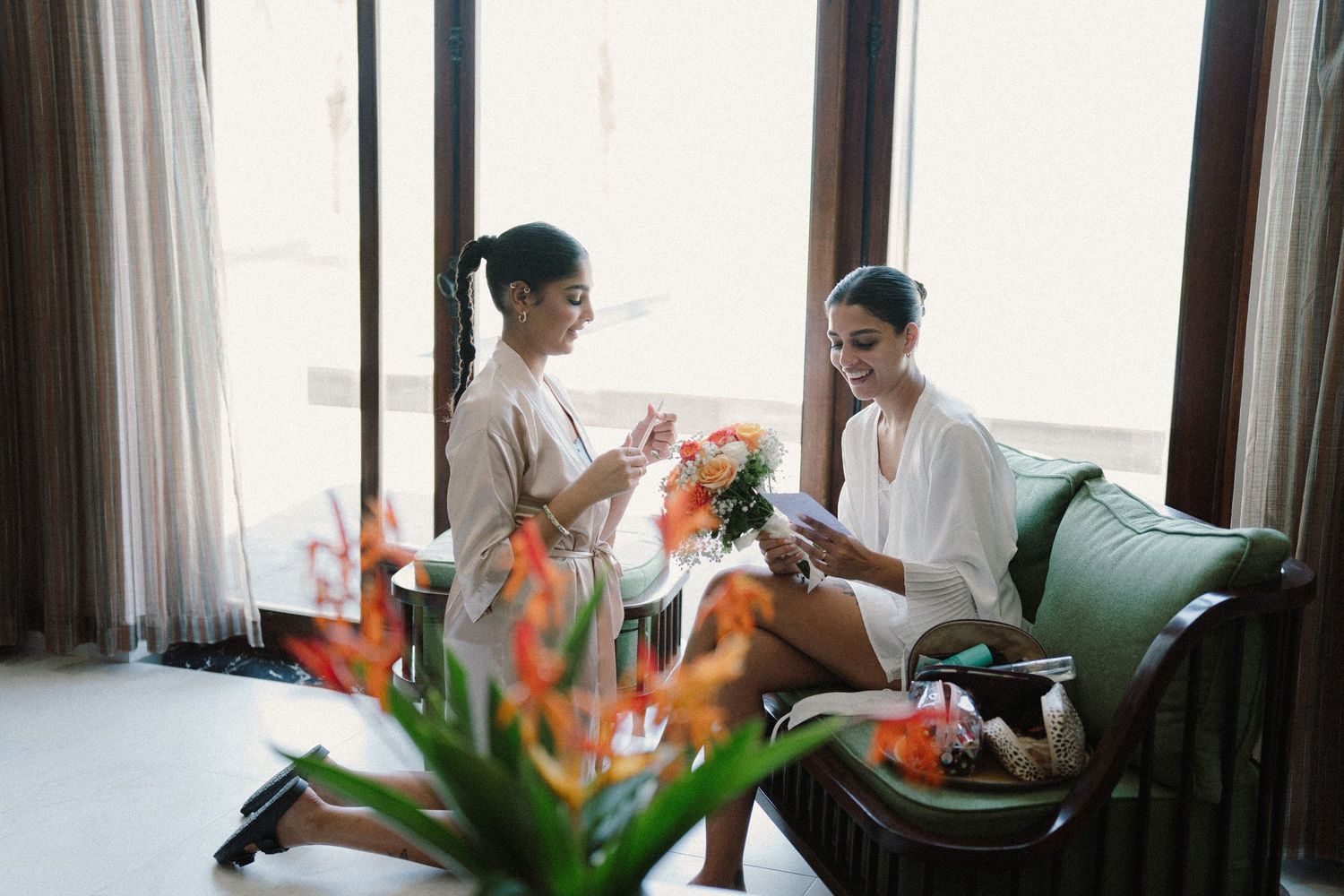 Group gets ready for wedding in sunny room with tropical flowers and curtains.