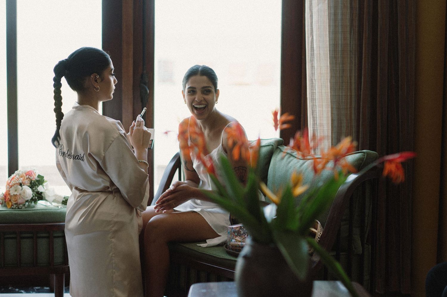 Wedding preparation scene near window with orange tropical flowers.