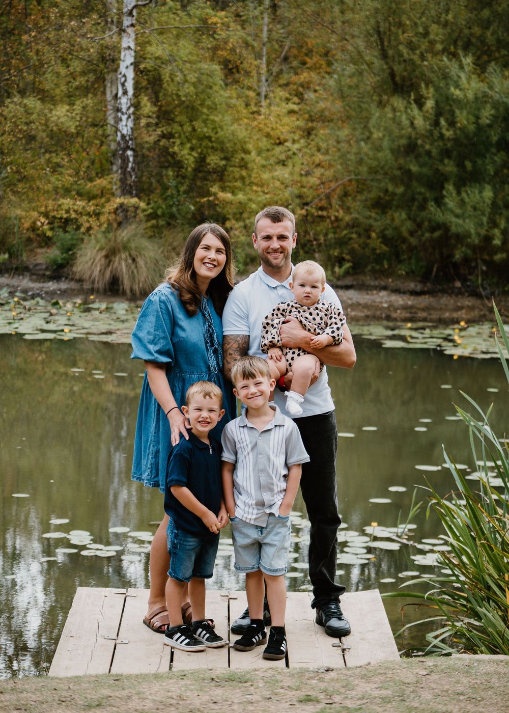 Family Photoshoot - Family poses together on wooden dock over pond with lily pads.