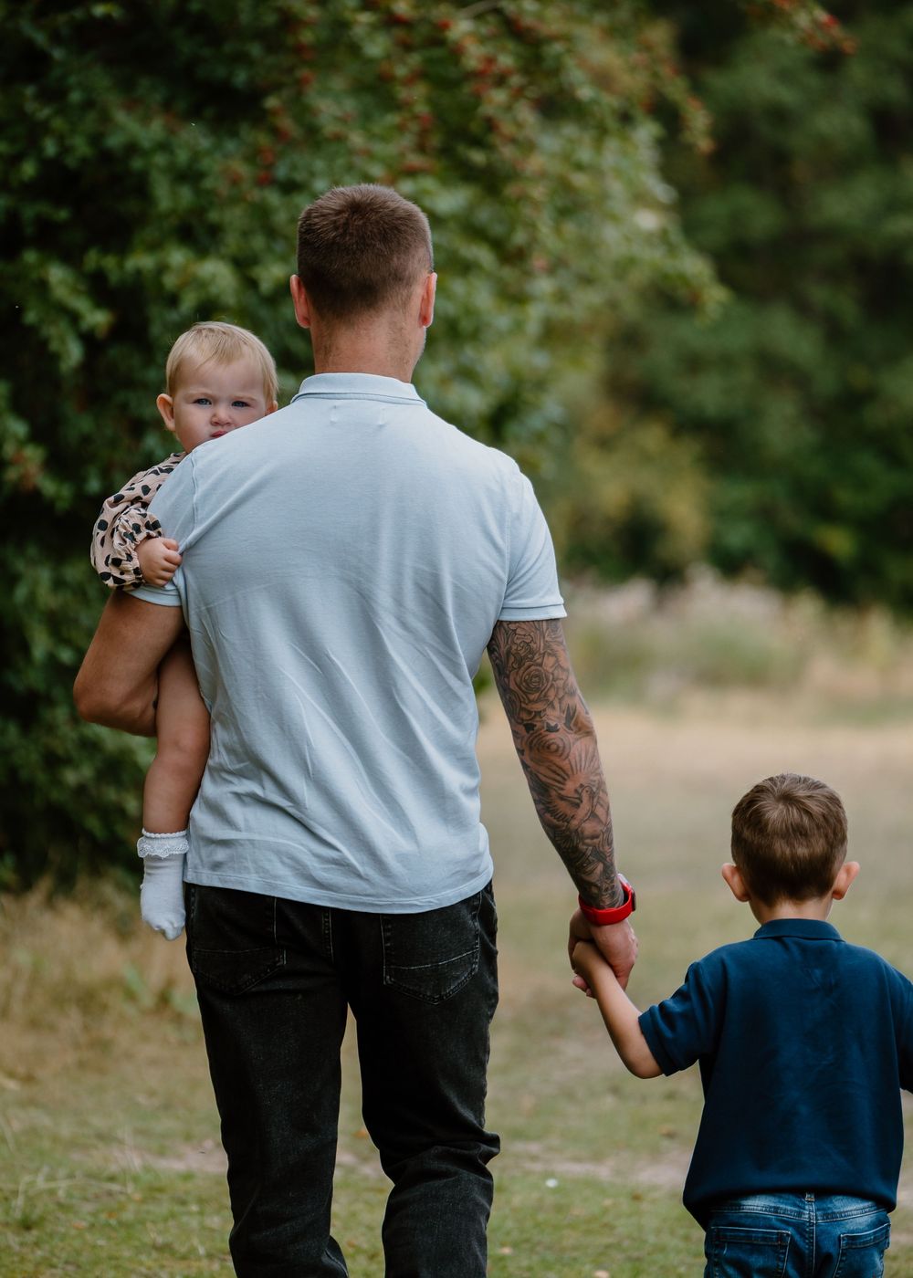 Family Photoshoot - Family walks away from camera holding hands along nature path.