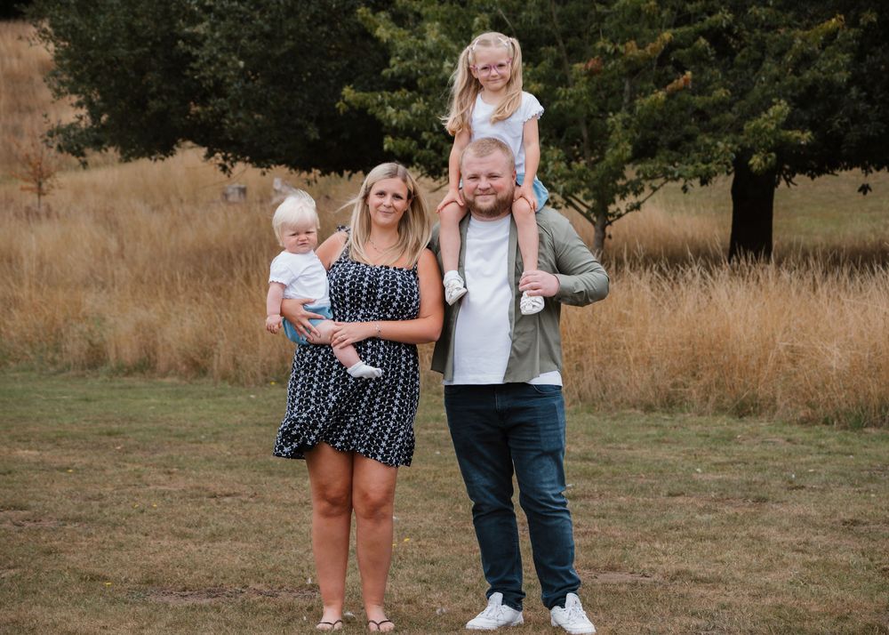 Family Photoshoot - Cusworth Hall - Family members walk together through a grassy field on sunny day.