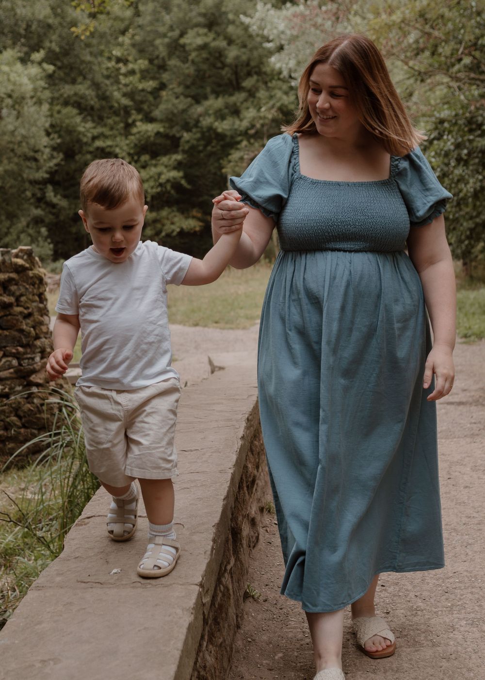 Family Photoshoot - Newmillerdam - A parent and child walking hand-in-hand along a stone path in nature wearing casual summer attire.