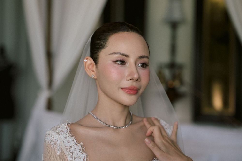 Bride in elegant lace dress poses in soft lighting.