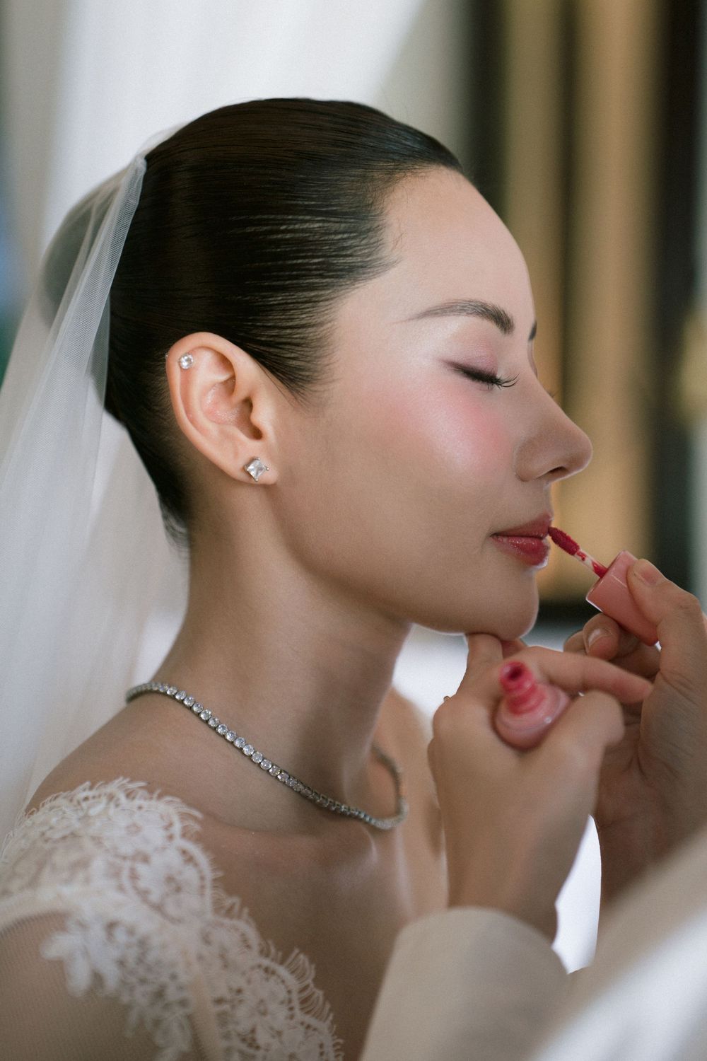 Close up profile view of a bride wearing white lace and crystal necklace during a romantic wedding moment.