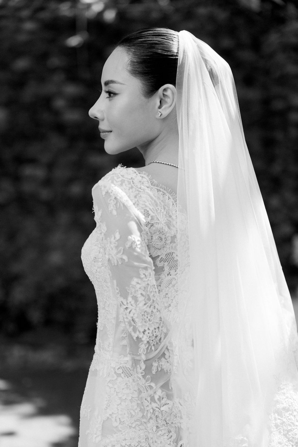 A delicate lace wedding gown and veil captured in black and white photography.
