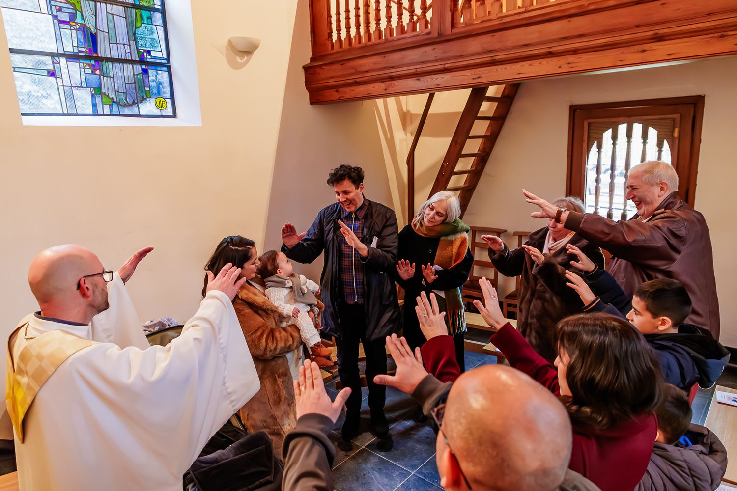 A group gathers together in a wooden loft-style room during what appears to be a celebratory moment.