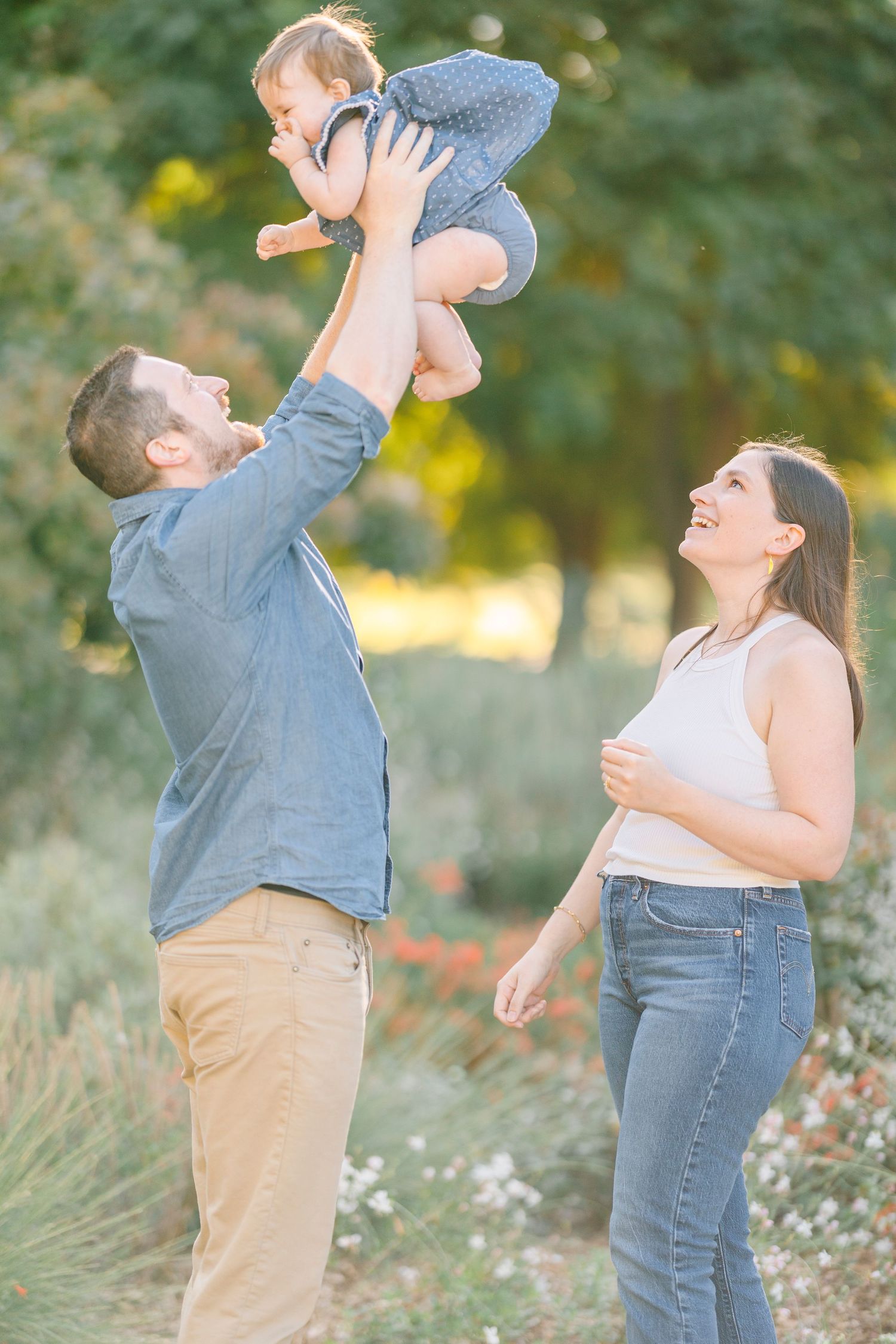 Playful family moment captured in a wildflower field during sunset.